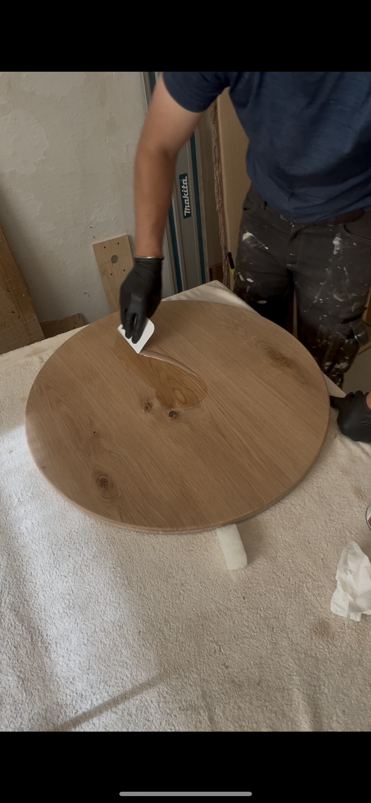 Närbild på händer som applicerar Osmo hårdvaxolja på en rund ekskiva, framhäver träets naturliga ådring och finish.