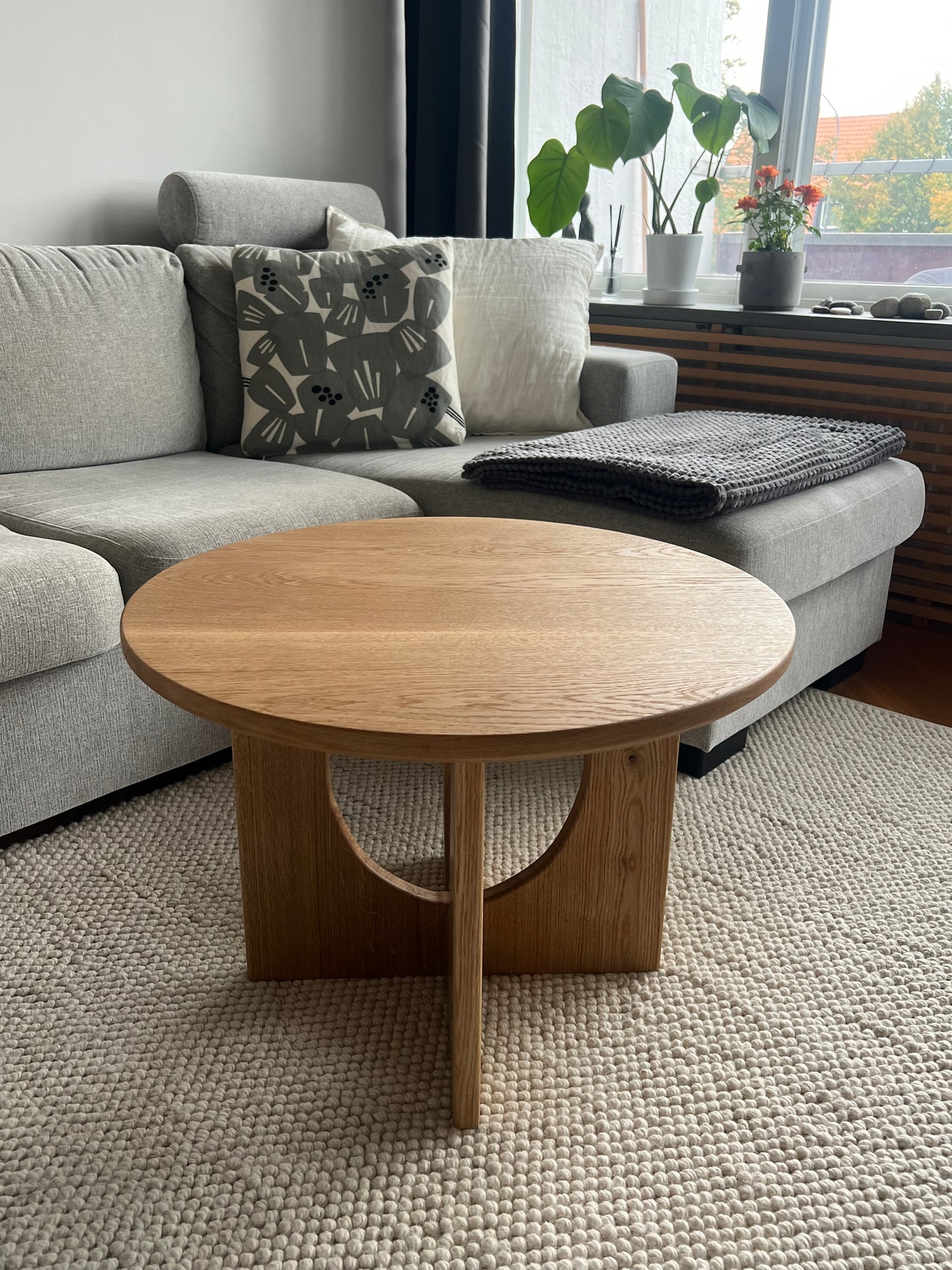 Runt bord Helge i massiv ek, fotograferat snett från sidan, framhäver bordets form, proportioner och den vackra trästrukturen.