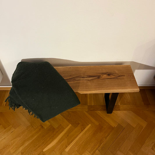 Bänk i massiv ek sedd framifrån, med slät sits och robusta ben, visar den naturliga trästrukturen.