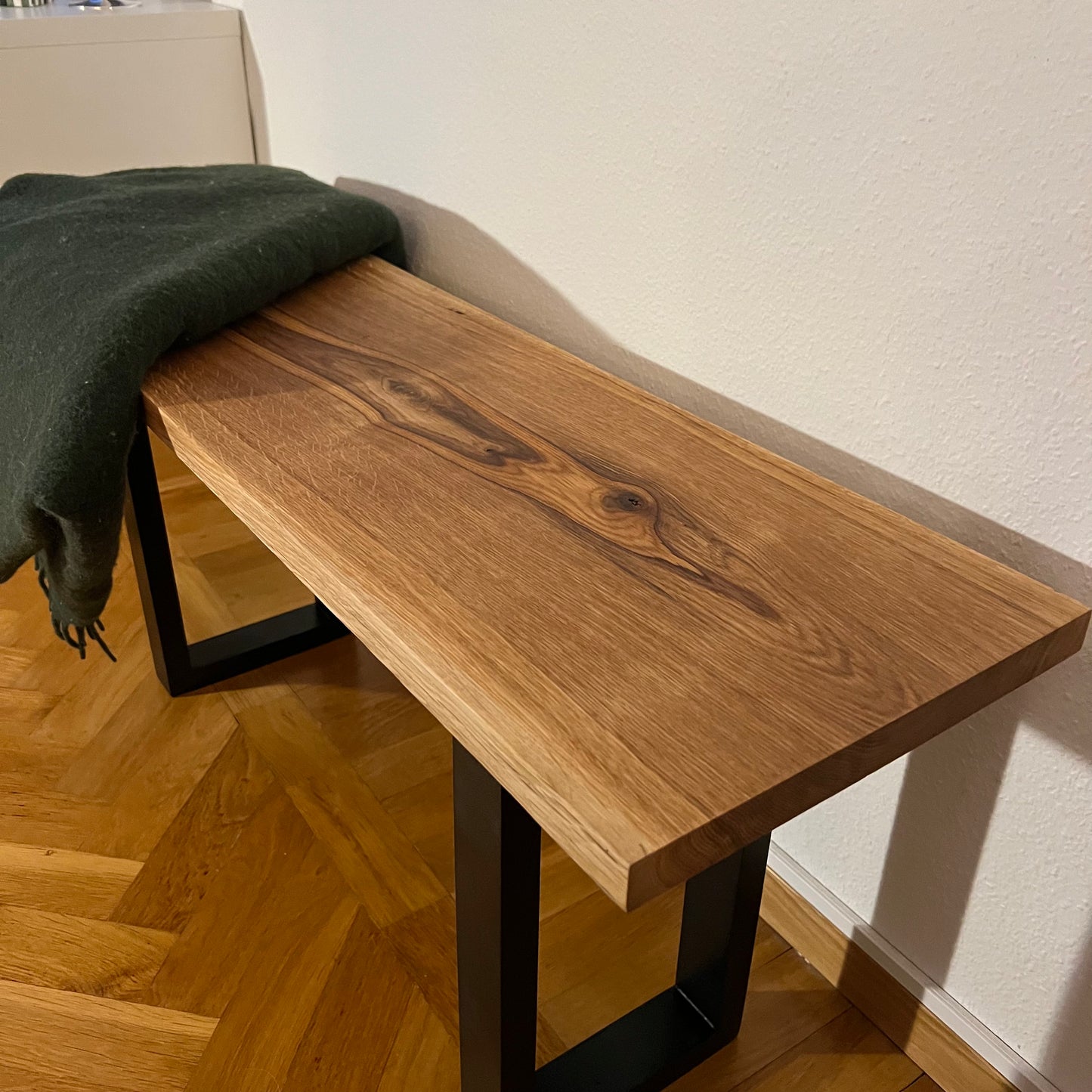Bänk i massiv ek fotograferad snett från sidan, framhäver den rena designen och de vackra ådringarna i träet.