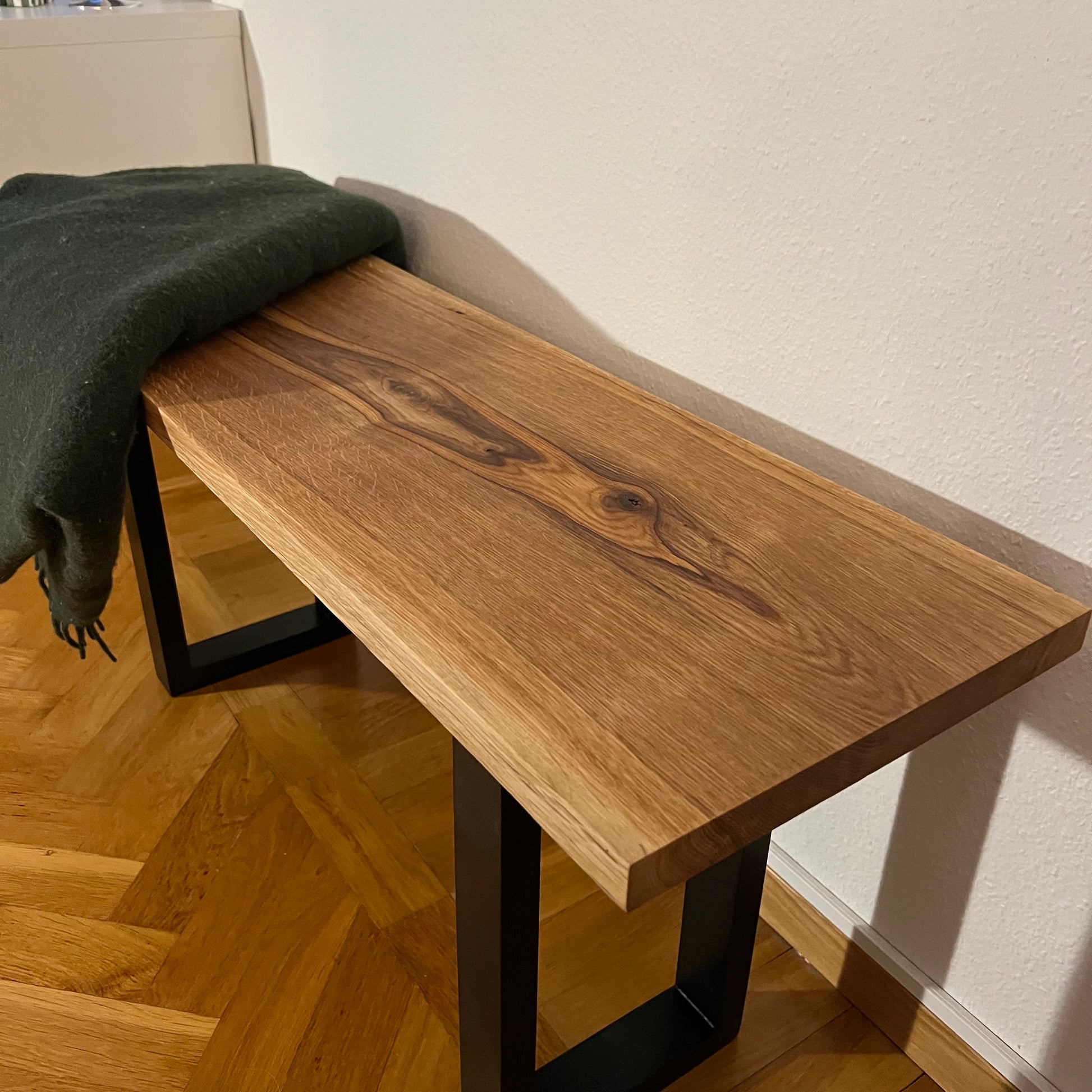 Bänk i massiv ek fotograferad snett från sidan, framhäver den rena designen och de vackra ådringarna i träet.