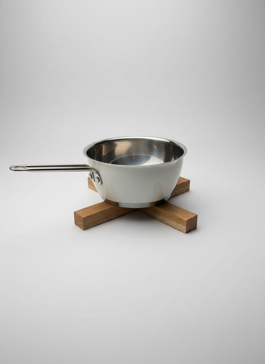 Grytunderlägg i massiv ek med en kastrull placerad ovanpå, visar hur underlägget används för att skydda ytor i köket.