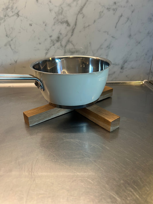 Grytunderlägg i massiv ek med naturlig trästruktur, stilrent och rustikt designat för att skydda bordet mot varma kastruller.