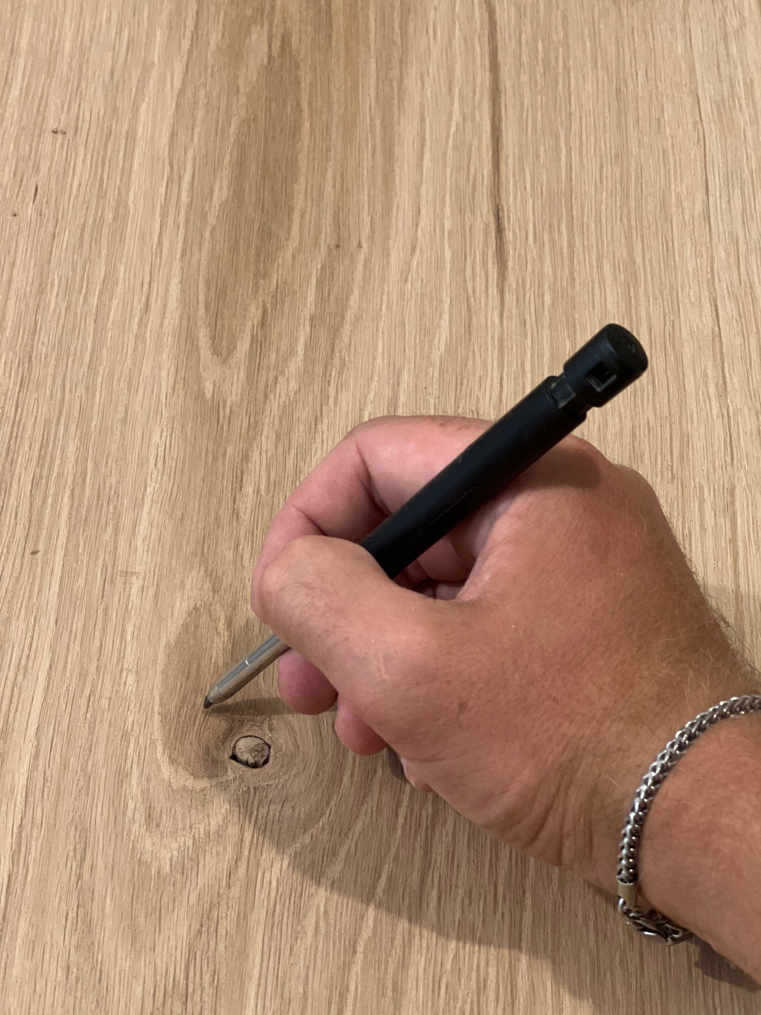 Närbild på en hand som håller en penna och börjar rita på en bit massiv ek, visar arbetsprocessen i snickeri och förberedelse för tillverkning.