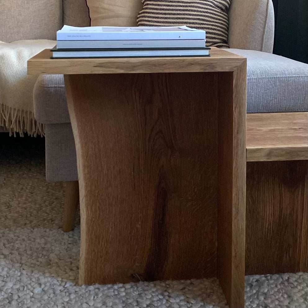 Sidobord Långvik i massiv ek, fotograferat framifrån, med två nivåer/avsatser och synlig träådring som ger en naturlig och tidlös känsla.