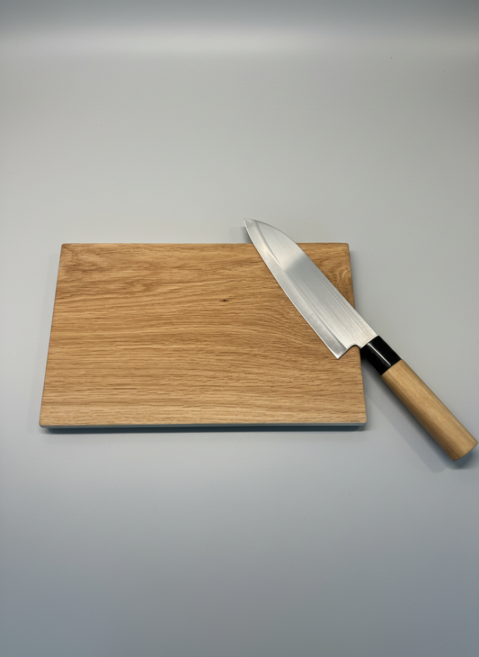 Skärbräda i massiv ek med en kniv placerad ovanpå, visar användningsområdet och den robusta kvaliteten.